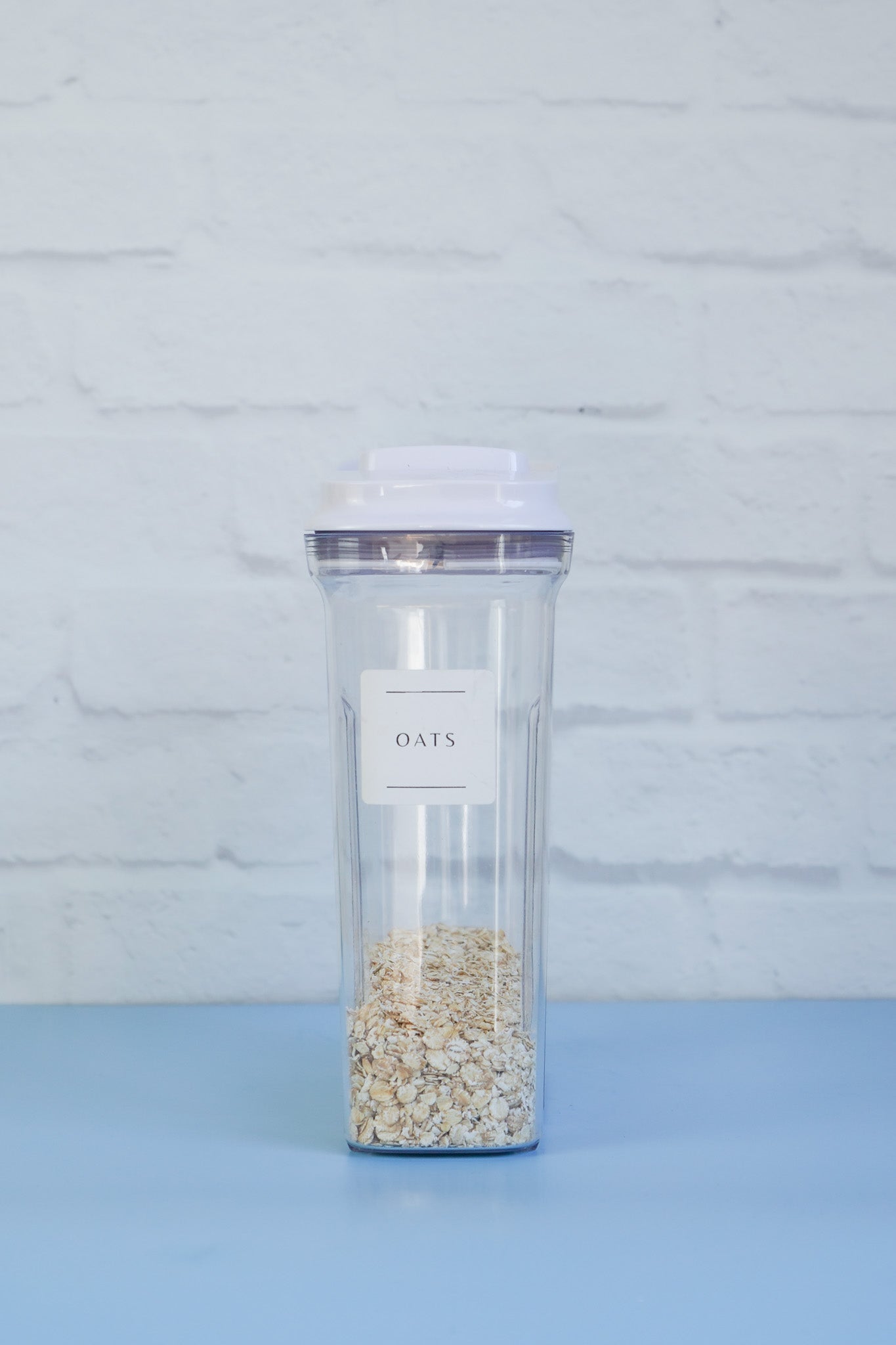 The OXO cereal container from The Little Pantry Project with oats inside and a label saying the words oats with two black lines under and above the word.