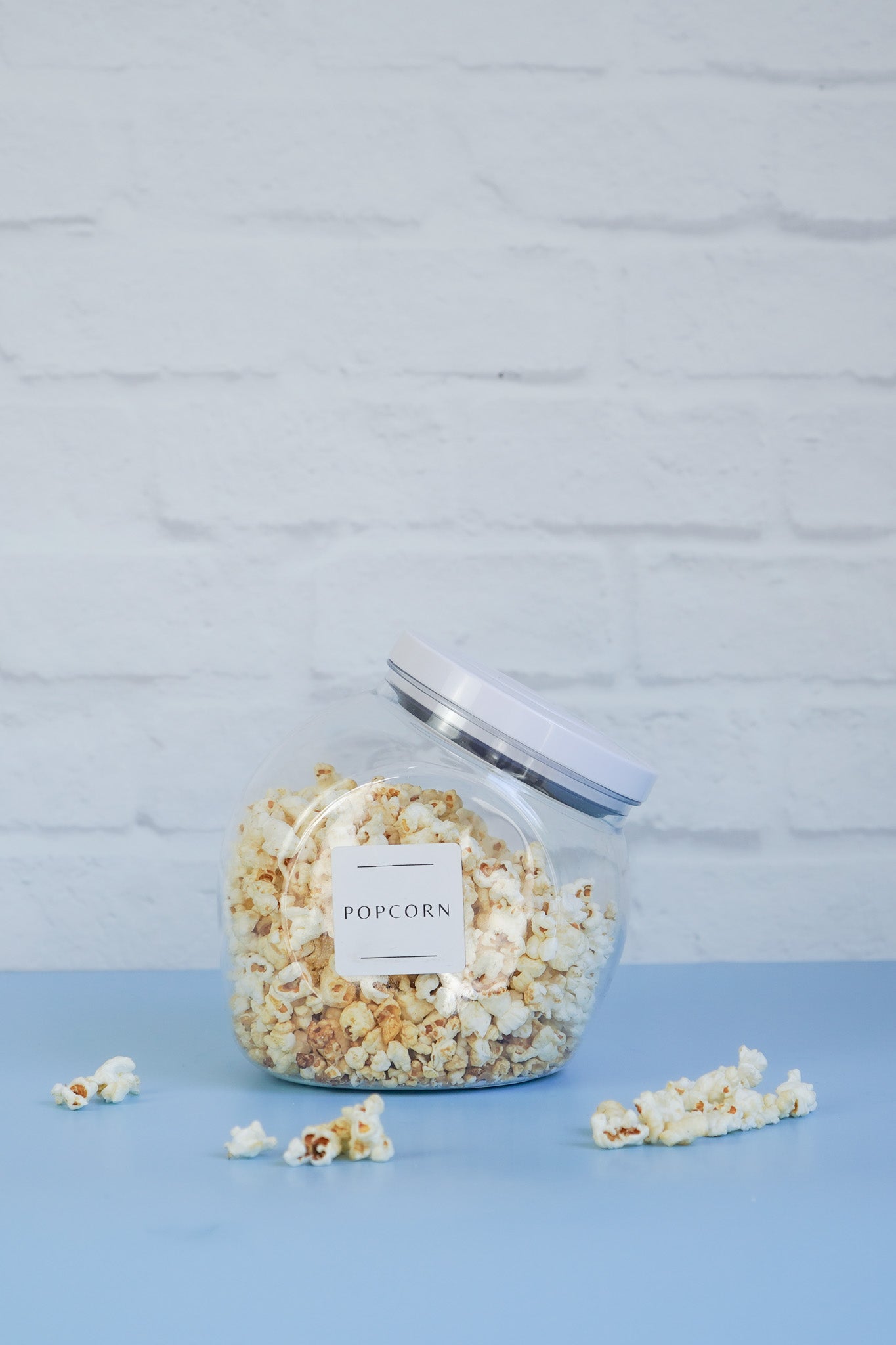 The OXO pop jar from The Little Pantry Project filled with popcorn with more scattered around the base.