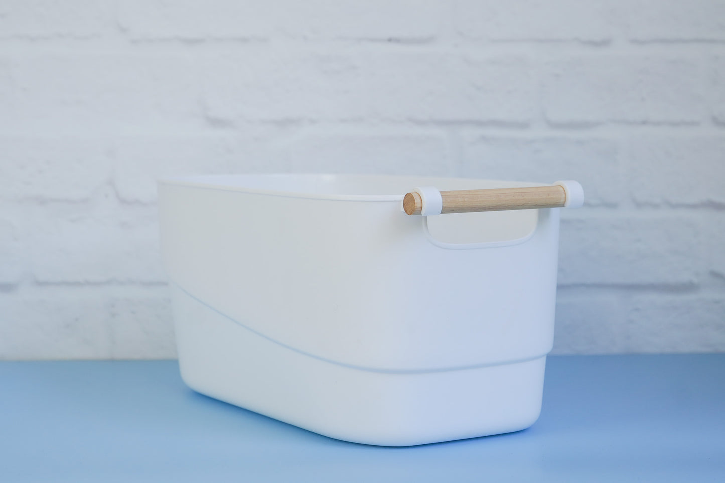 The white tub with wooden handle from The Little Pantry Project on 45 degree angle.