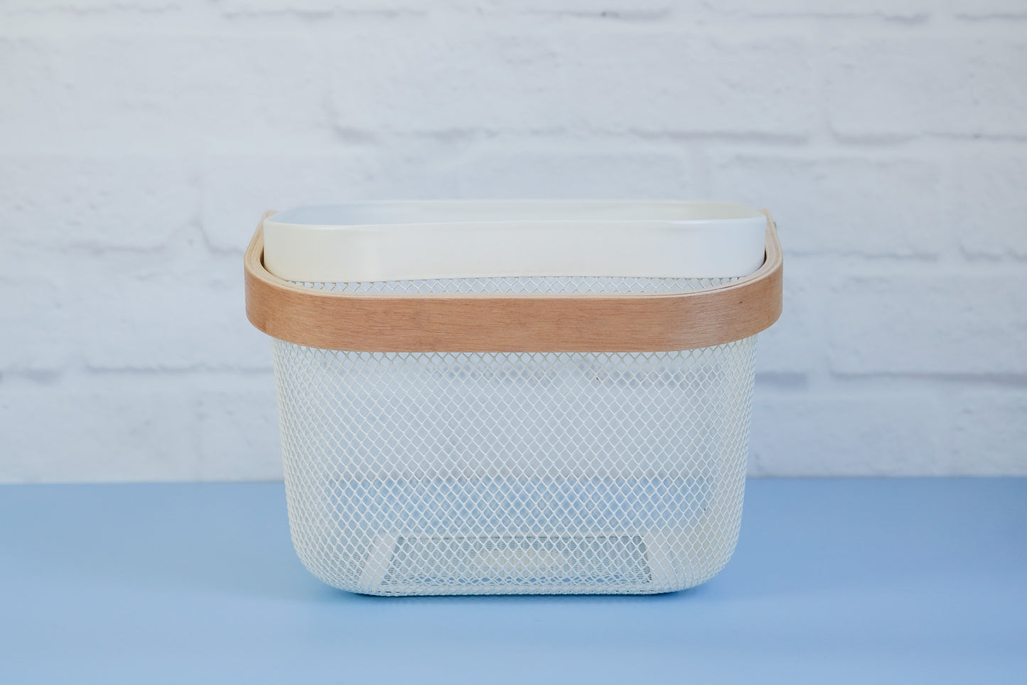 The white mesh basket with wooden handle from The Little Pantry Project from side.