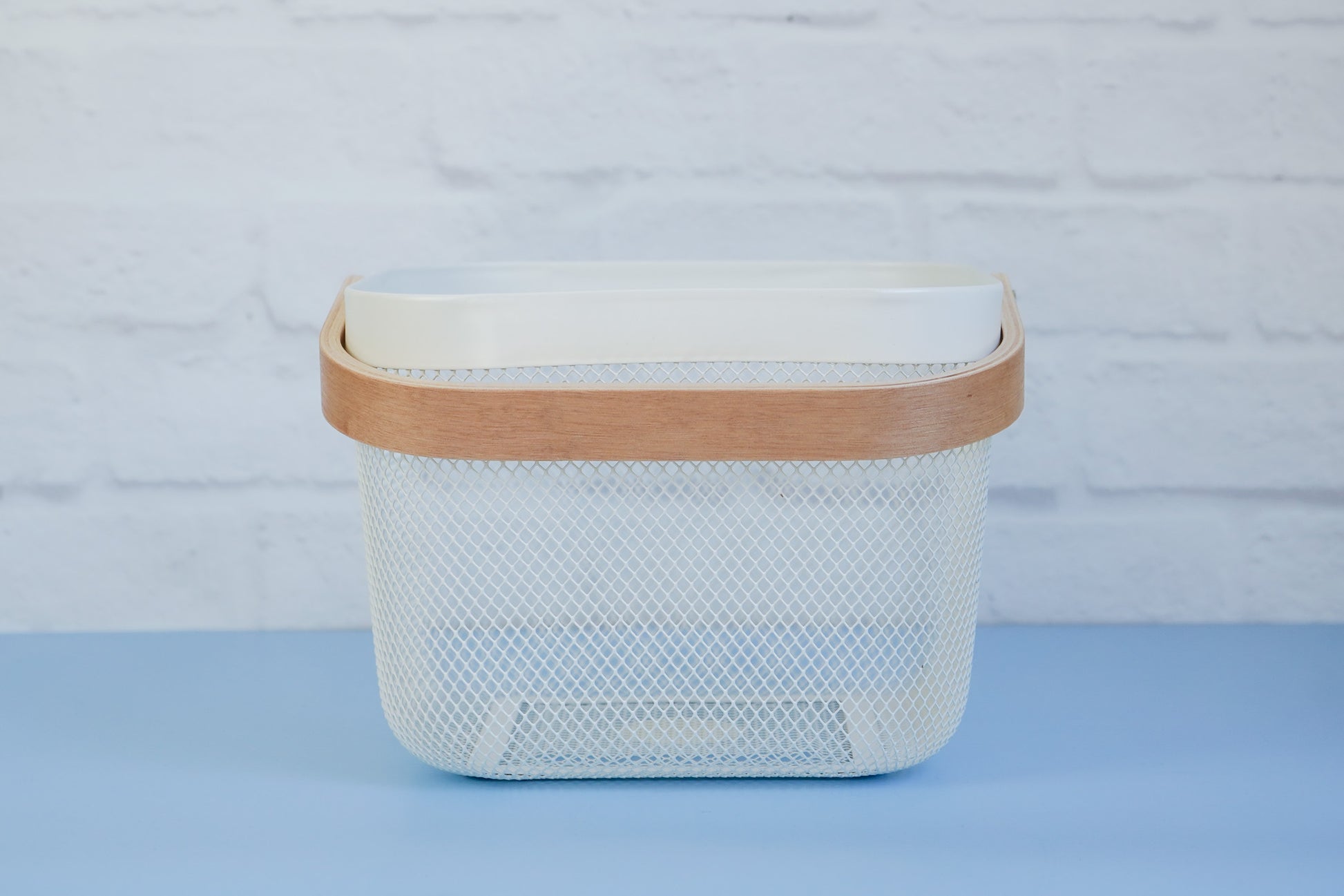 The white mesh basket with wooden handle from The Little Pantry Project from side.